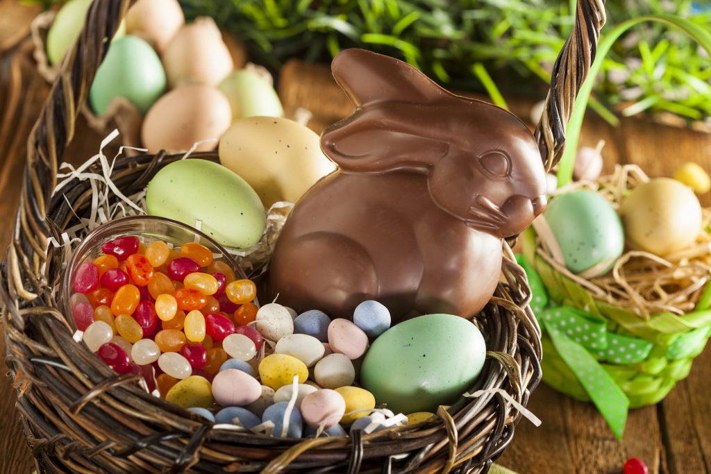 Chocolate Easter Bunny in a basket with other candy like jelly beans and chocolate eggs.